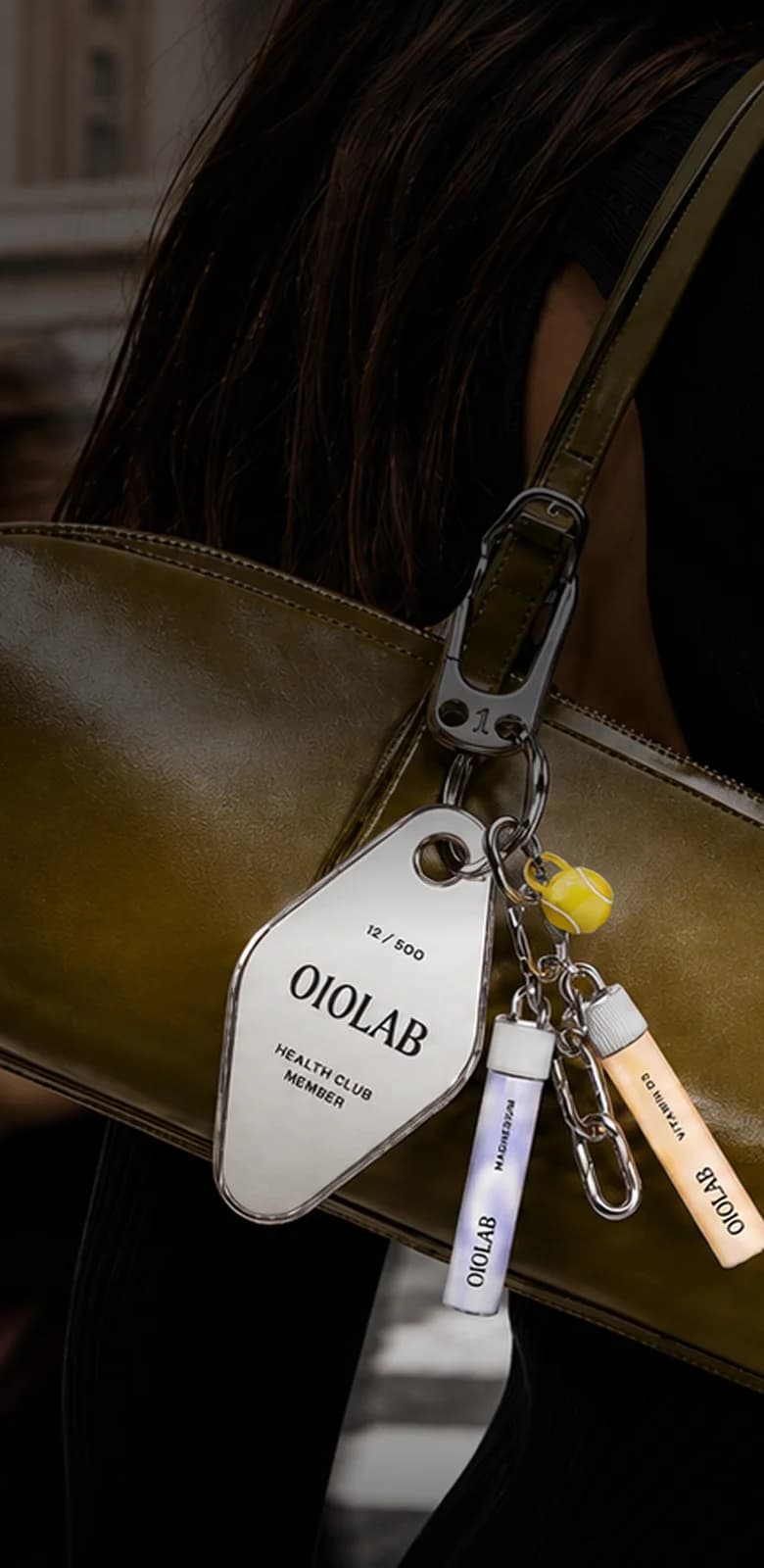 010LAB health-club keychain tag and cartridge charms clipped to a shoulder bag on a city street