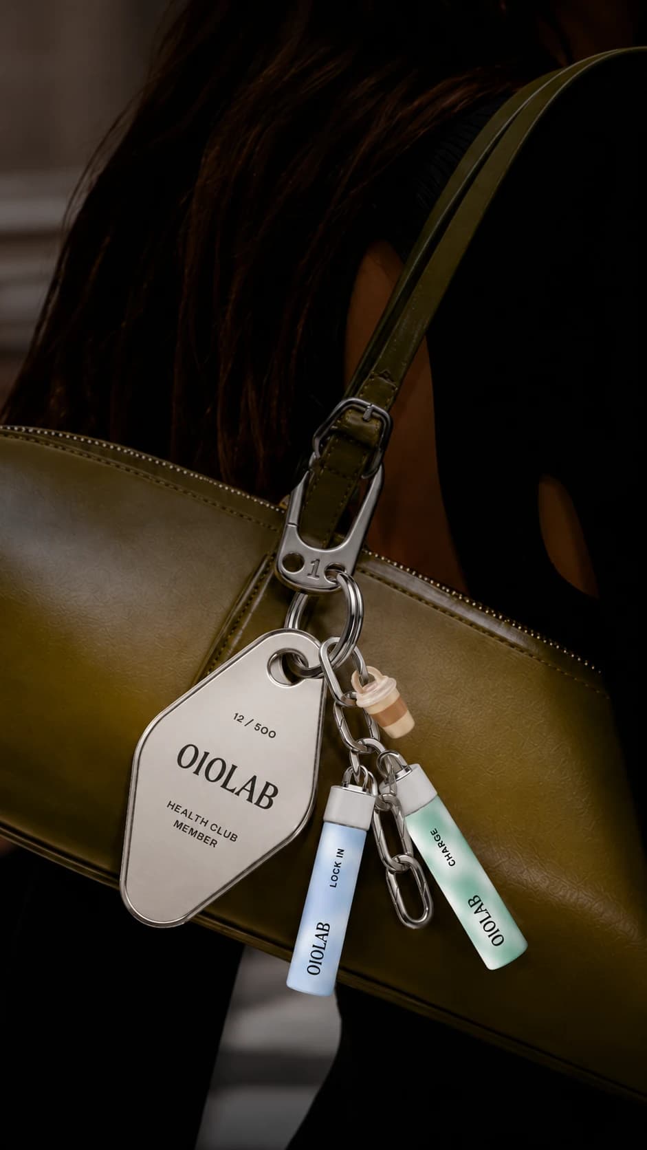 010LAB health-club keychain tag and cartridge charms clipped to a shoulder bag on a city street
